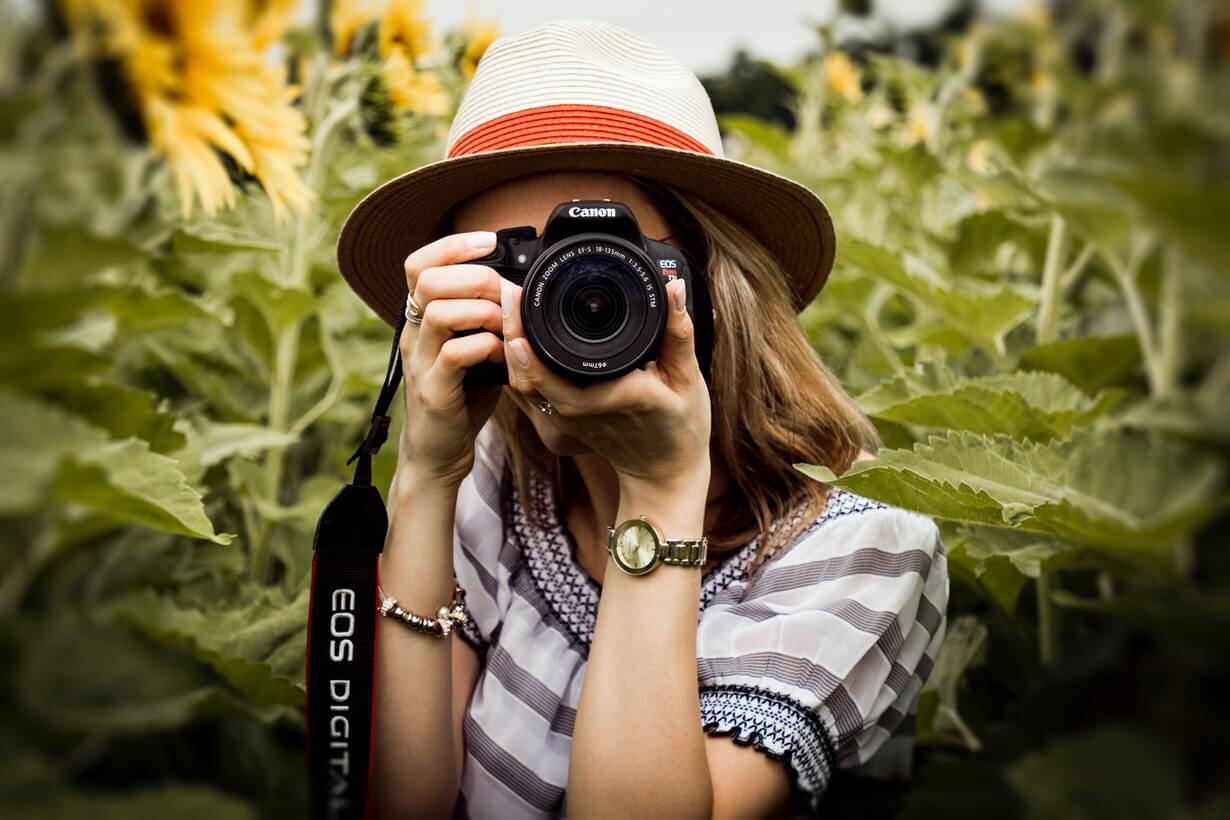 Frau mit Fotoapparat zwischen Sonnenblumen
